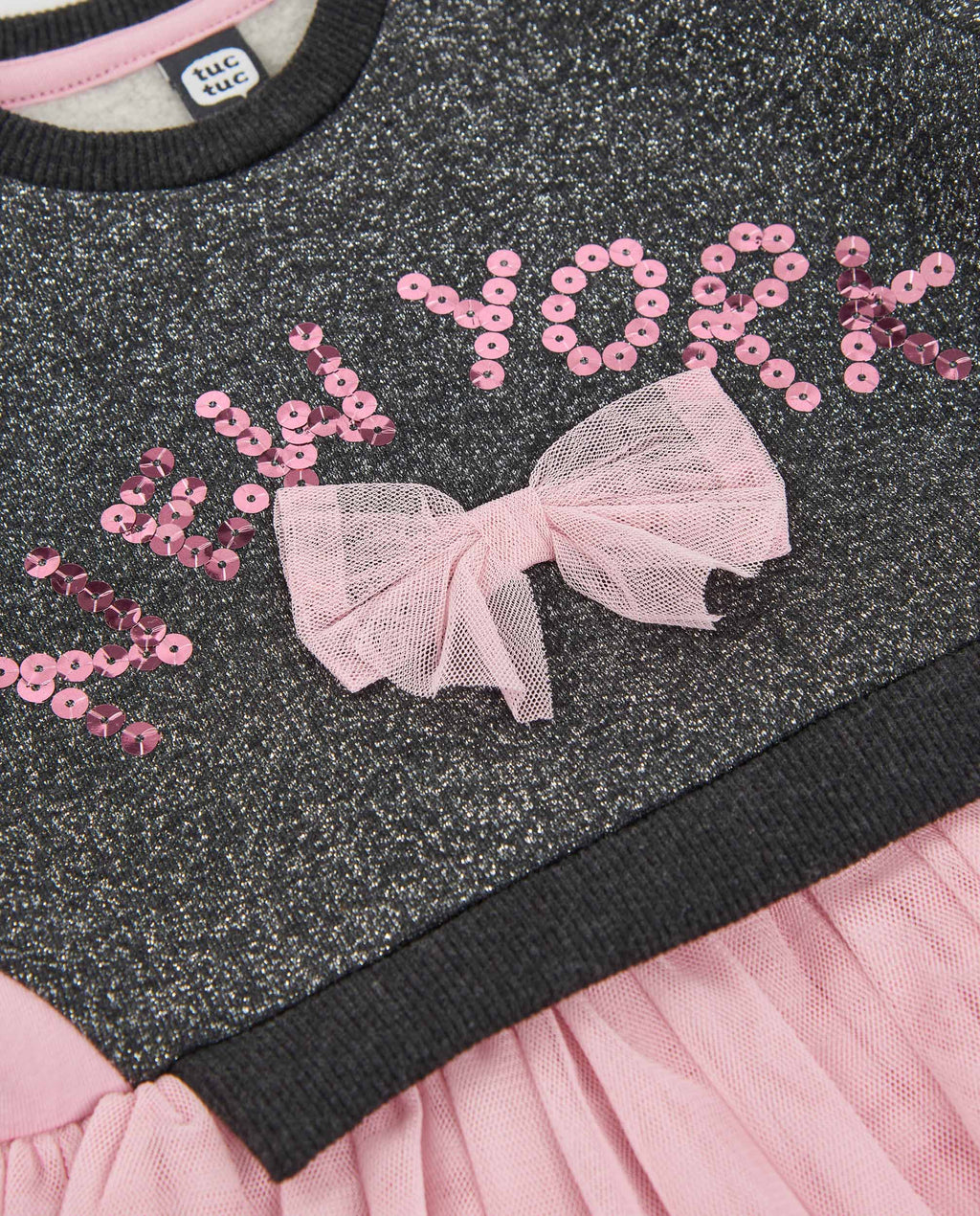 Göğüsteki pembe payetli New York yazısı ve tül fiyonk detayı yakın plandan görünüyor.