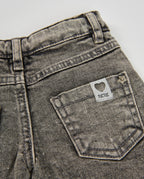 Pantolonun arka cebi yakın planda; kalp logolu TUCTUC etiketi ve ağartmalı denim dokusu görünüyor.