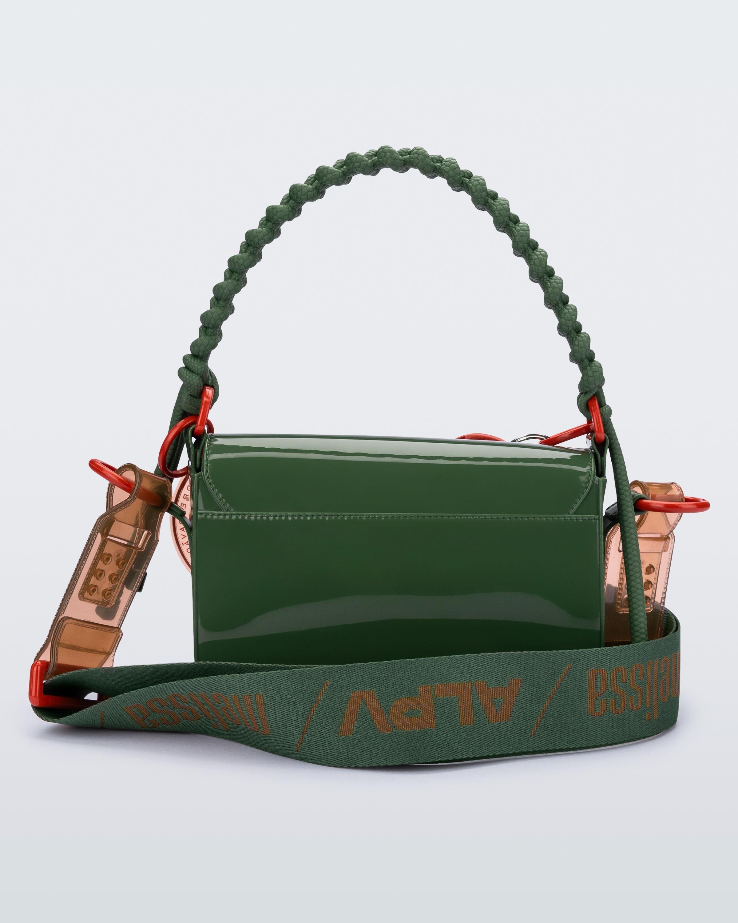 Koyu yeşil parlak Melflex yüzeyli Melissa çanta arka görünüm. Geniş tekstil omuz askısı ve turuncu metal bağlantı halkaları.