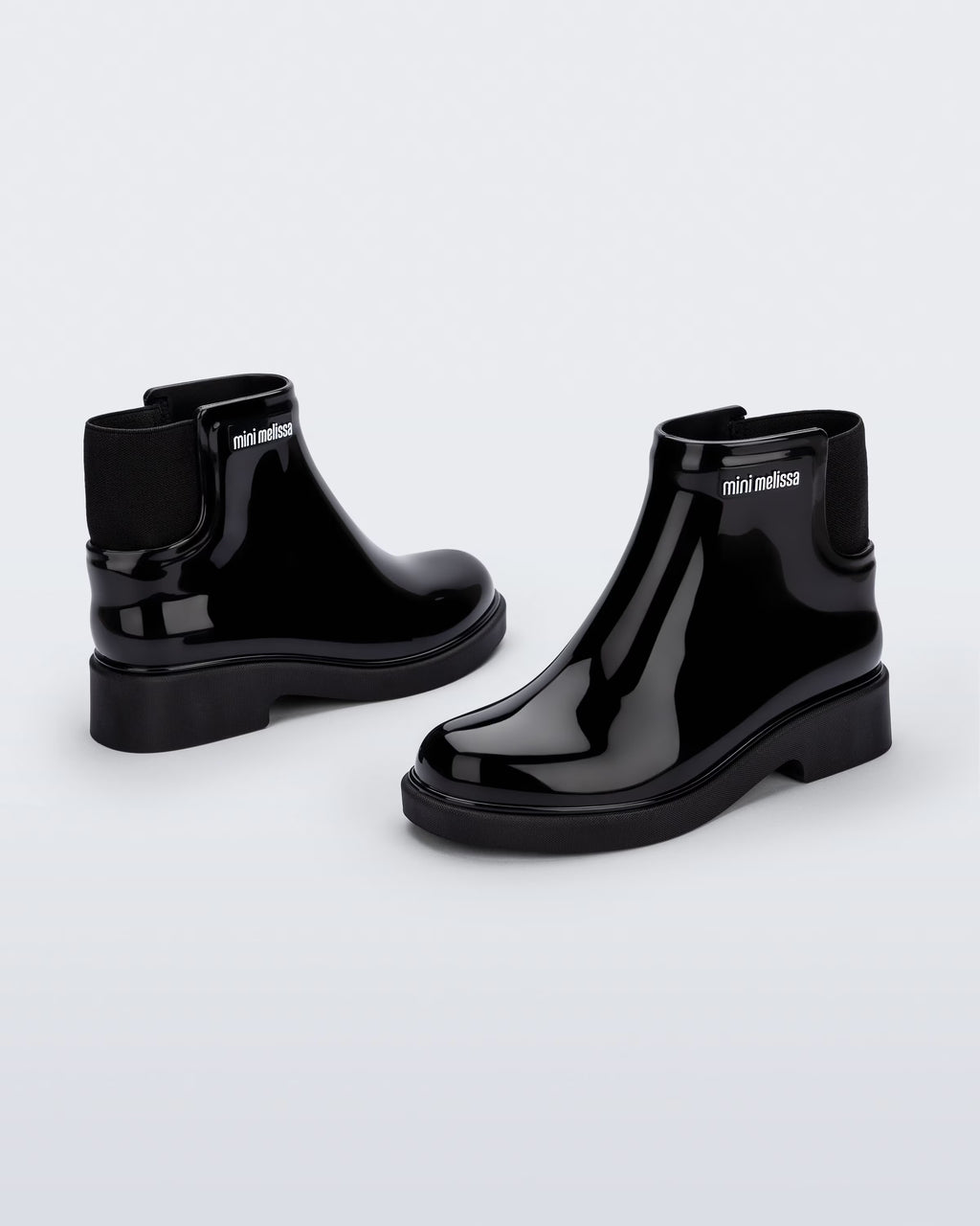 Siyah Mini Melissa Chelsea Boot II çocuk çifti üstten açıyla; örgü bilek manşeti net şekilde öne çıkıyor.