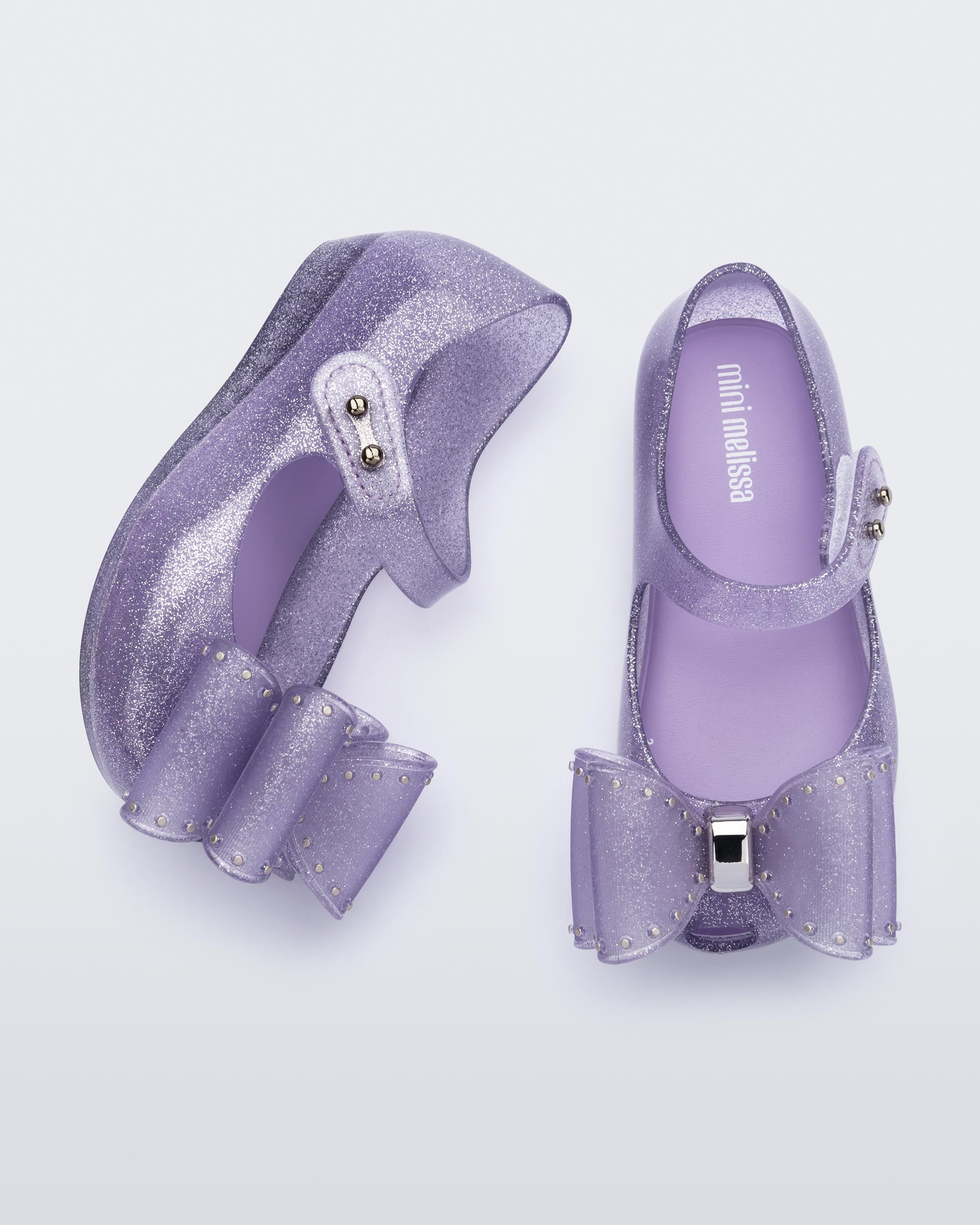 Mini Melissa Ultragirl lila simli babet üstten görünüm büyük fiyonk aplikesi ve velcro sistem detayı