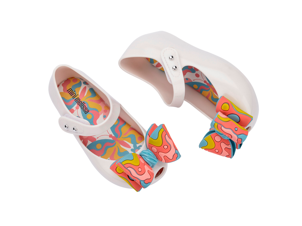 Mini Melissa Ultragirl Wonderland BB beyaz pembe fiyonklu çocuk ayakkabı – üstten görünüm, pastel pembe-beyaz fiyonk detaylı, renkli iç taban tasarımlı, pratik cırt cırt bantlı model