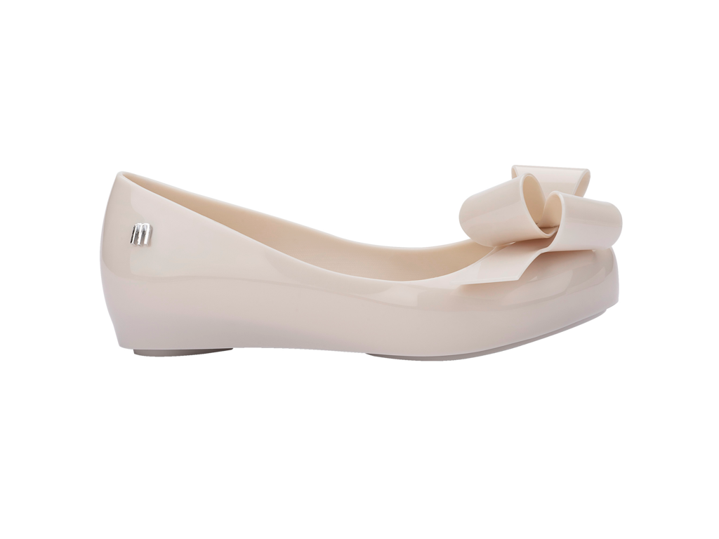 Mini Melissa bej balerin ayakkabı, yan görünüm, parlak malzeme ve ikonik fiyonk tasarımlı
