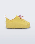 Mini Melissa Bloomy Sneaker sarı kız bebek ayakkabısı, çiçek bağcıklı tasarımıyla yan açıdan görünüyor.