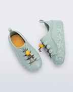 Mini Melissa Bloomy Sneaker'ın elastik bağcık ve sarı çiçek toggle detayı yakın planda görünüyor.