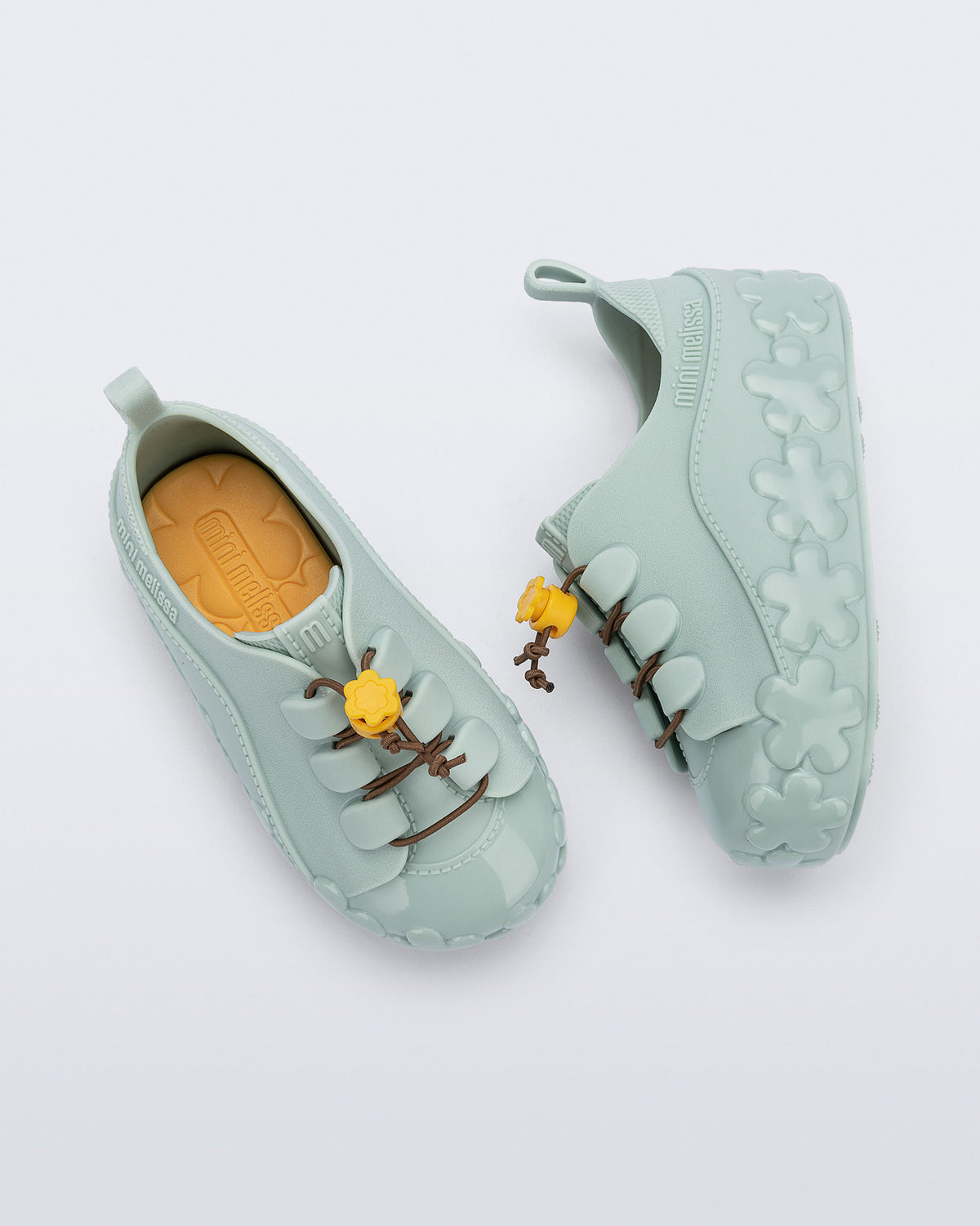 Mini Melissa Bloomy Sneaker'ın elastik bağcık ve sarı çiçek toggle detayı yakın planda görünüyor.