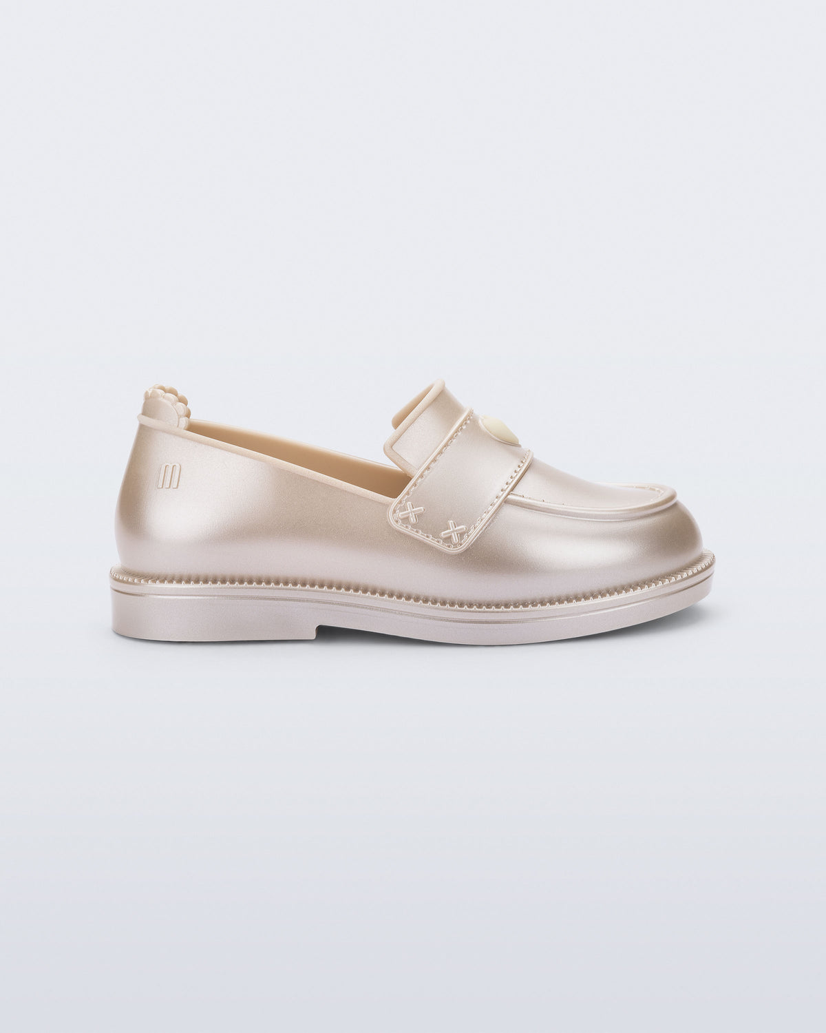 Mini Melissa Royal Love sedef şampanya babet, kalp rozetli loafer tasarımıyla yan açıdan görünüyor.