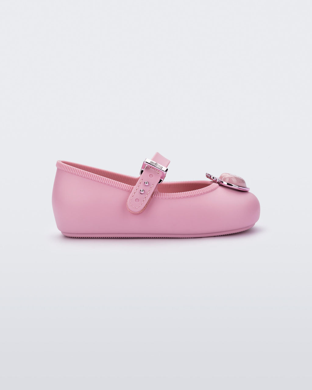 Mini Melissa Soft Ballerina Princess pembe babet, simli kalp aplikeli burun detayı ve metalik tokasıyla yan açıdan görünüyor.