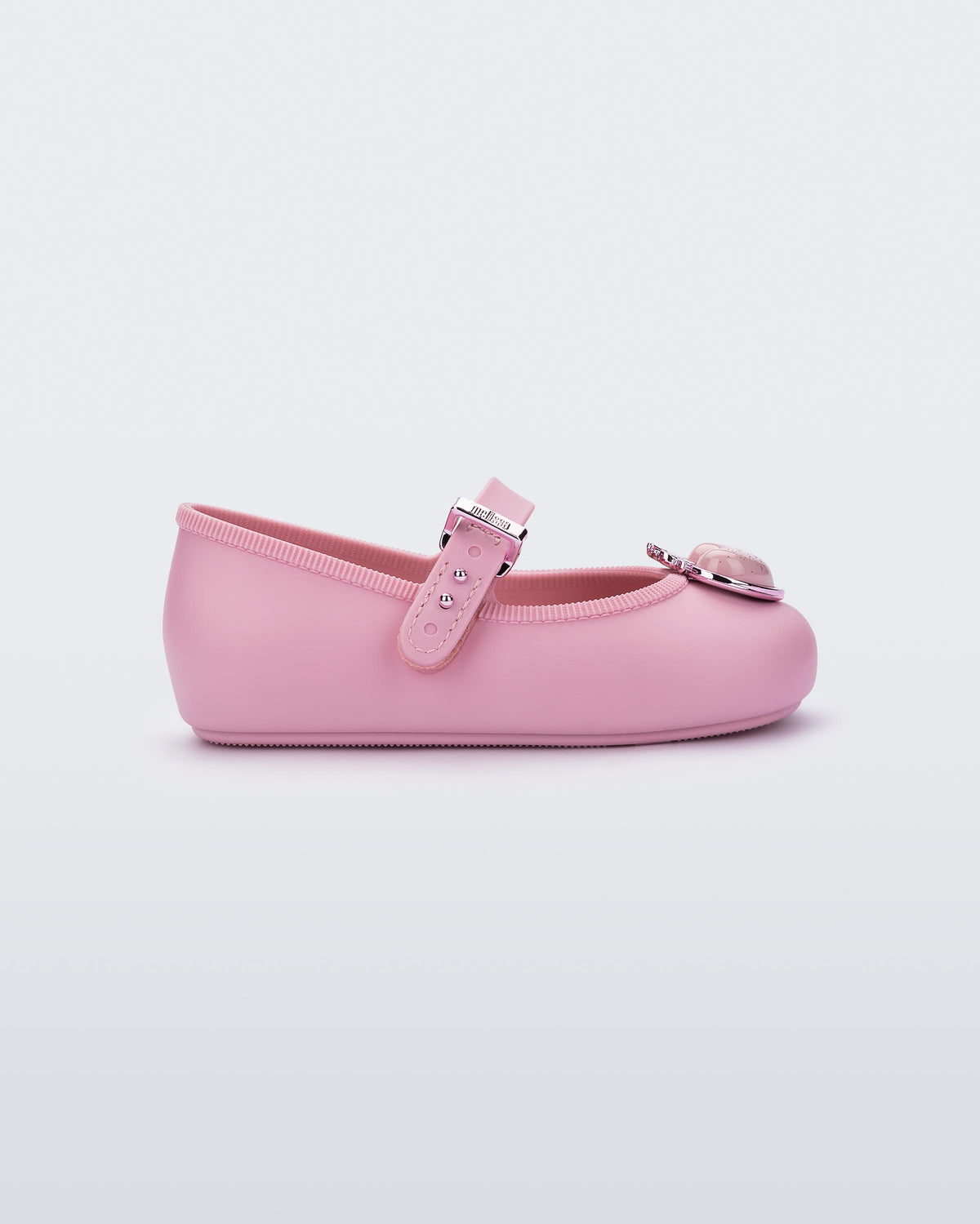 Mini Melissa Soft Ballerina Princess pembe babet, simli kalp aplikeli burun detayı ve metalik tokasıyla yan açıdan görünüyor.