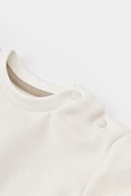 BabyCosy ekru bebek sweatshirtinin omuz çıtçıtlı yakası, yakın çekim