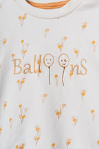 Ekru organik pamuk bebek sweatshirt üzerindeki "Balloons" yazı nakışı ve mikro sarı çiçek desenleri yakın plan