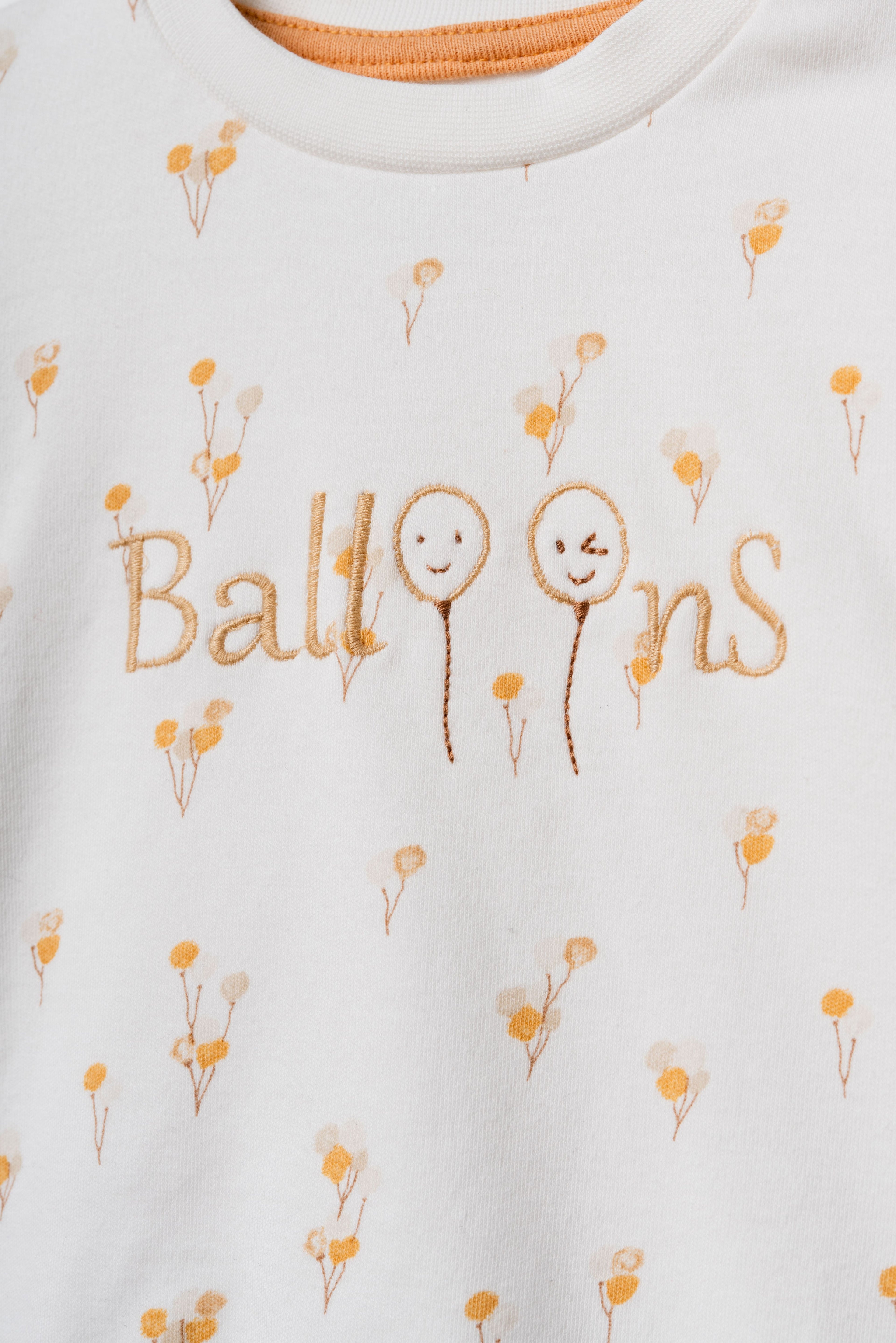 Ekru organik pamuk bebek sweatshirt üzerindeki "Balloons" yazı nakışı ve mikro sarı çiçek desenleri yakın plan