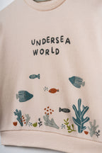 Pudra peach organik pamuk bebek sweatshirtü, göğüsteki Undersea World yazısı ve deniz altı illüstrasyonu yakın çekim