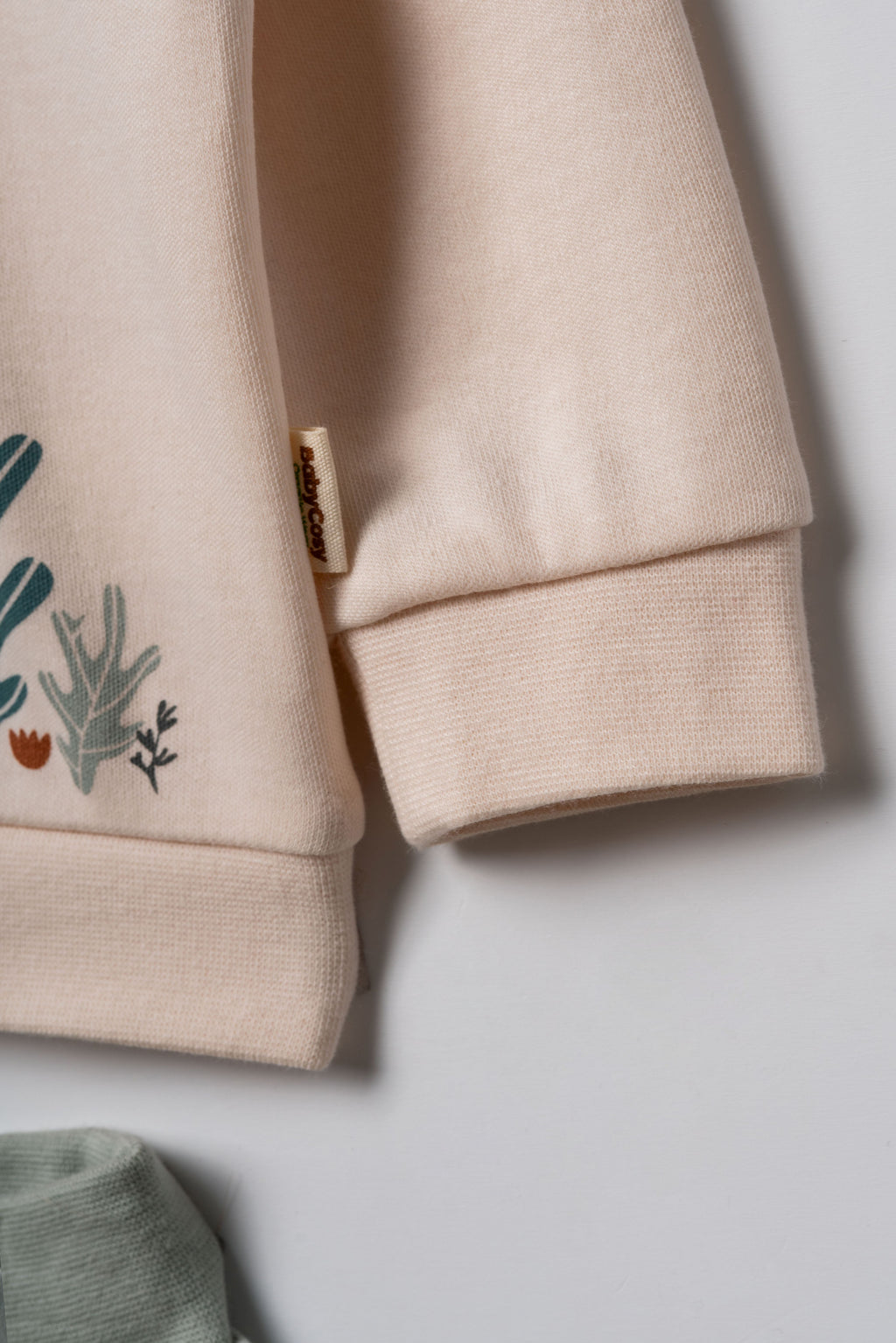 Pudra peach organik pamuk bebek sweatshirtü kol detayı, ribana manşet ve yumuşak interlok kumaş yakın çekim