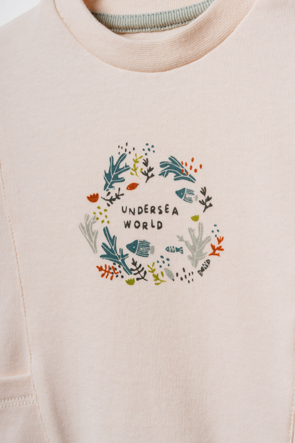 Pudra peach organik pamuk bebek sweatshirtü, göğüsteki Undersea World çelenk baskısı ve deniz altı illüstrasyonu yakın çekim