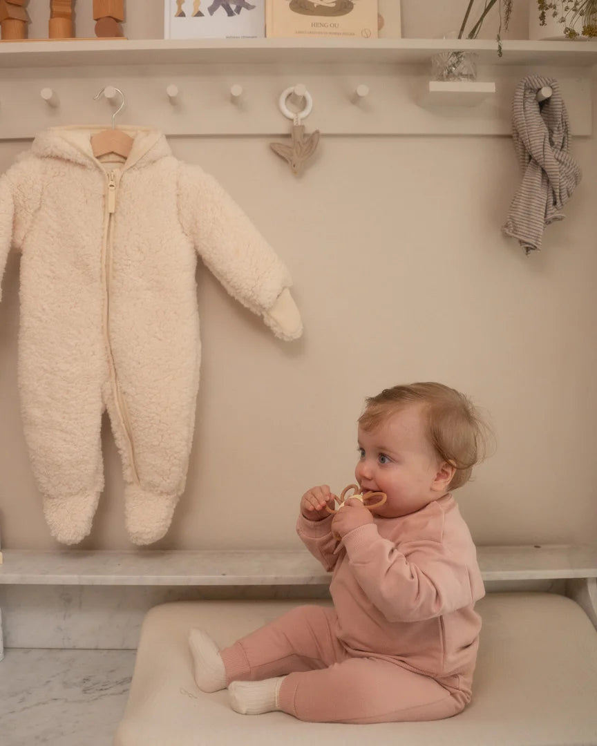 Dirkje pudra pembe sweatshirt ve eşofman altı takımı bebeğin üzerinde; alt ve üst aynı tonda, tam boy görünüyor.