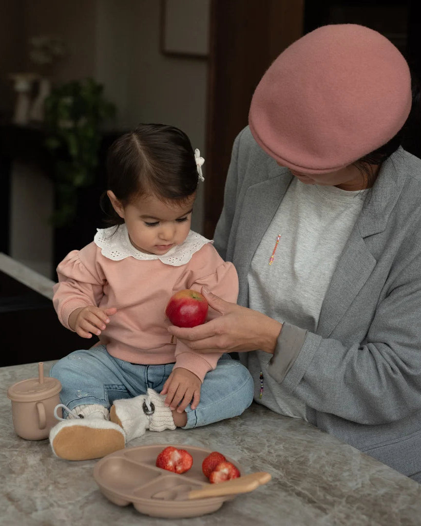Dirkje pudra pembe broderie bebe yakalı sweatshirt bebeğin üzerinde; mutfak tezgâhında annesiyle, balon kollar görünüyor.
