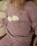 Dirkje lila sweatshirt kız çocuk üzerinde yakın planda; bubble tea baskısının kabartmalı krem köpük dokusu görünüyor.