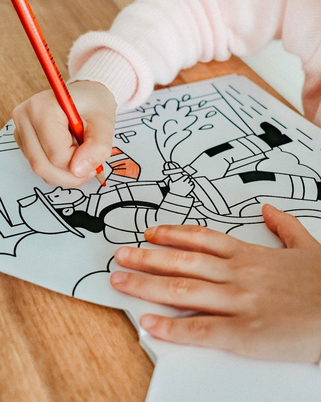 Çocuk eli turuncu kuru boyayla itfaiyeci çizimini boyuyor