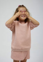 Miela Kids açık pembe kapitone şort etek, model üzerinde aynı renk sweatshirt ile kombin