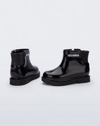Siyah Mini Melissa Chelsea Boot II çifti üstten açıyla; örgü bilek manşeti net şekilde öne çıkıyor.