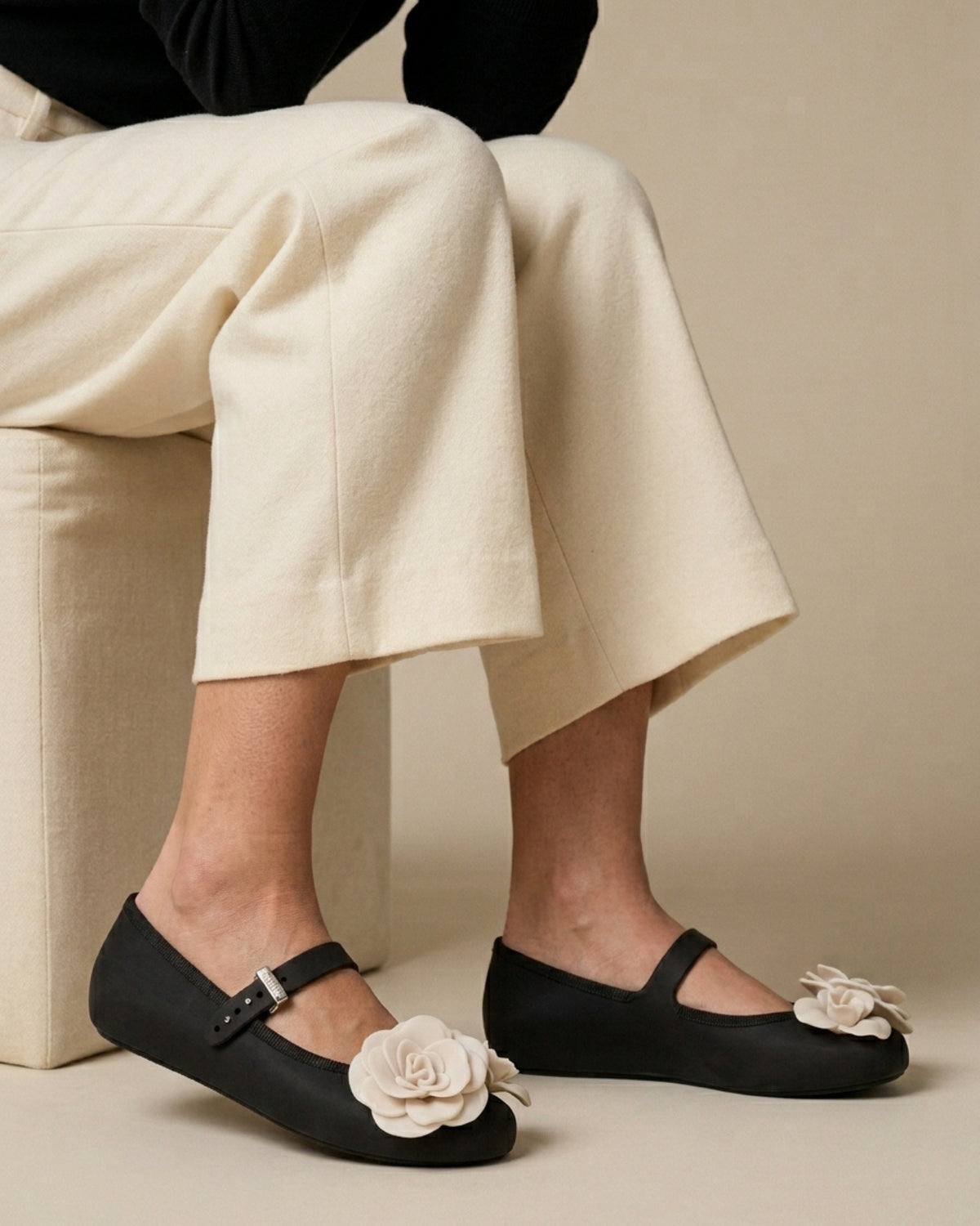 Krem pantolon ve açık bilekle giyilmiş siyah bantlı babet; Melissa Soft Ballerina Petals'ın ayaktaki gerçek oranı.