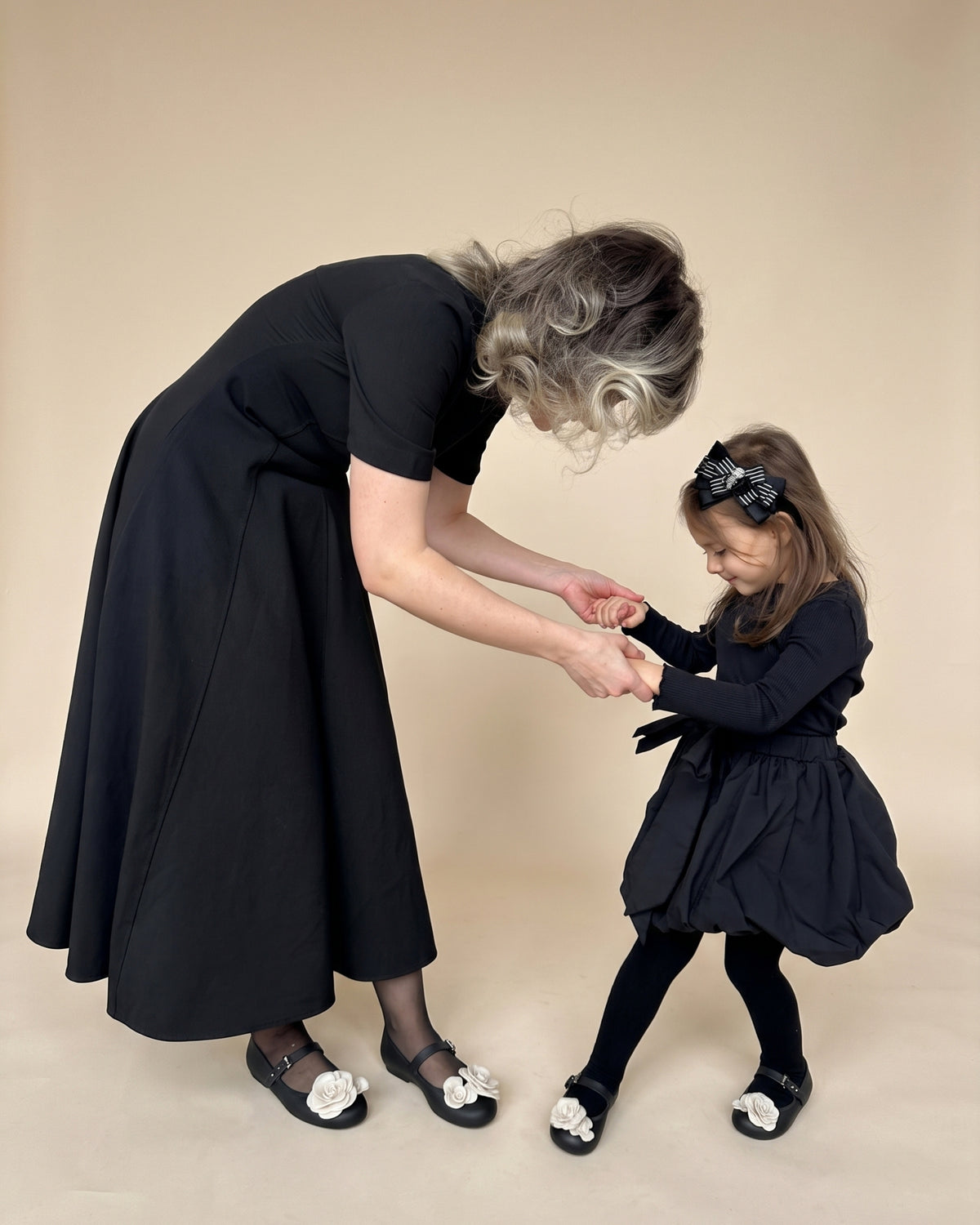 Anne ve kızı eşleşen siyah çiçekli babetlerle el ele; Melissa ve Mini Melissa anne kız kombini.