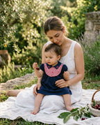 Anne kucağında kiraz tutan Miela Kids Golden Childhood elbiseli bebek, bahçe sabahı