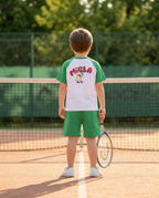 Miela Kids tennis takımlı erkek çocuk tenis kortunda arkadan, raket elinde duruyor