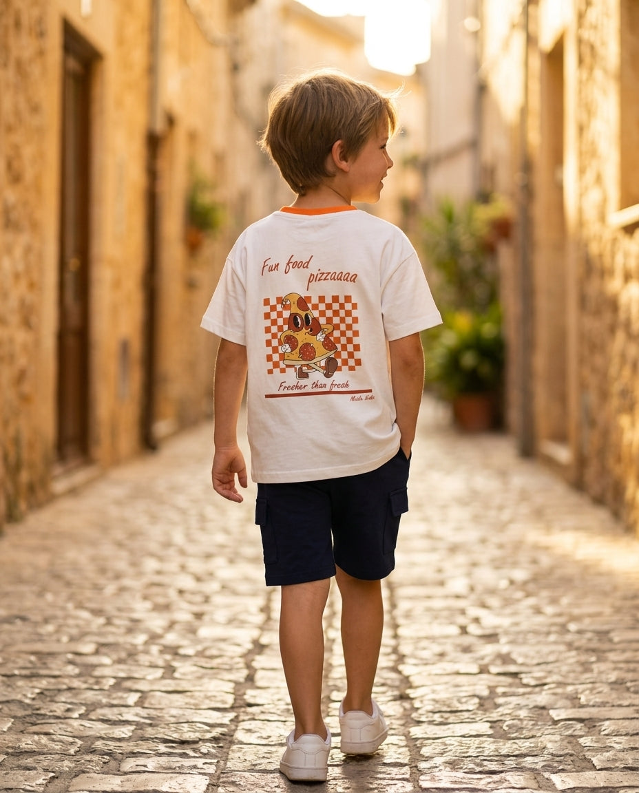 Miela Kids pizza baskılı beyaz tişört ve lacivert cargo şort takım giyen erkek çocuk taş sokakta yürüyor, arka baskı görünümü