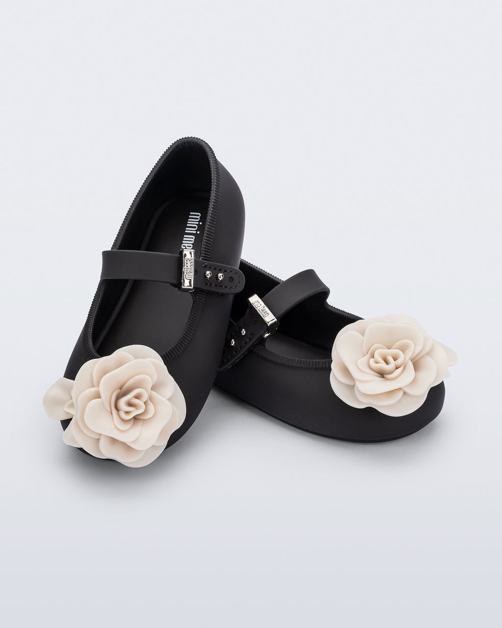 Mini Melissa Soft Ballerina Petals mat siyah babet, krem gül aplikesiyle çapraz önden görünüyor.