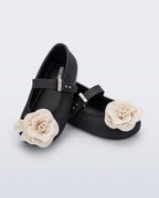 Mini Melissa Soft Ballerina Petals mat siyah babet, krem gül aplikesiyle çapraz önden görünüyor.