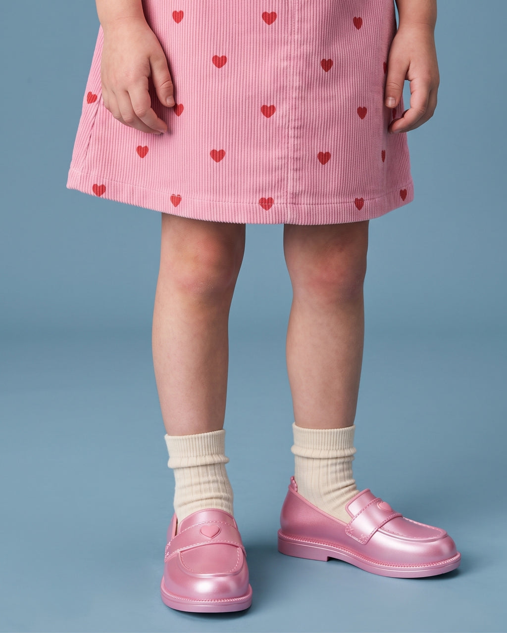 Mini Melissa kız çocuk loafer detayı: sedefli pudra pembe kalp düğmeli model, X dikiş izleri, tırtıklı welt bandı ve krem çorap.