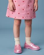 Mini Melissa kız çocuk loafer detayı: sedefli pudra pembe kalp düğmeli model, X dikiş izleri, tırtıklı welt bandı ve krem çorap.