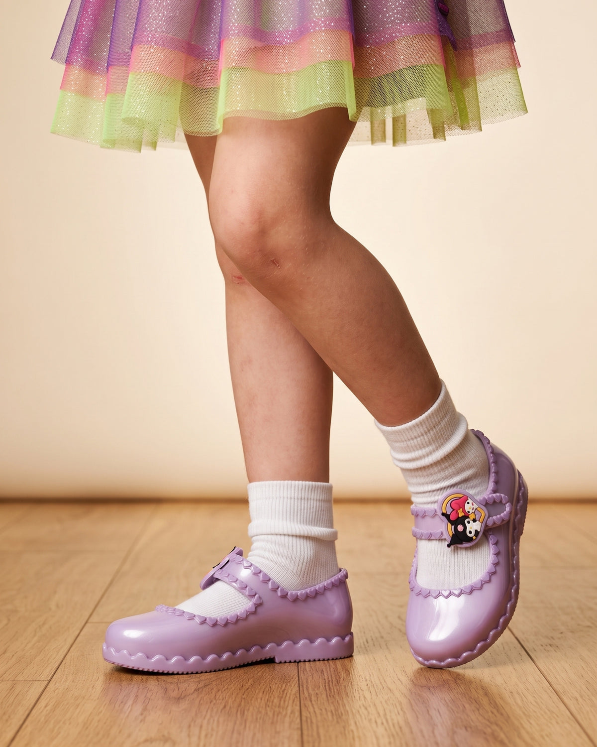 Mini Melissa mor ayakkabı modeli, lila sedefli çocuk babeti; kalp kabartmalı bant, beyaz çorap ve tüllü etek detayı.