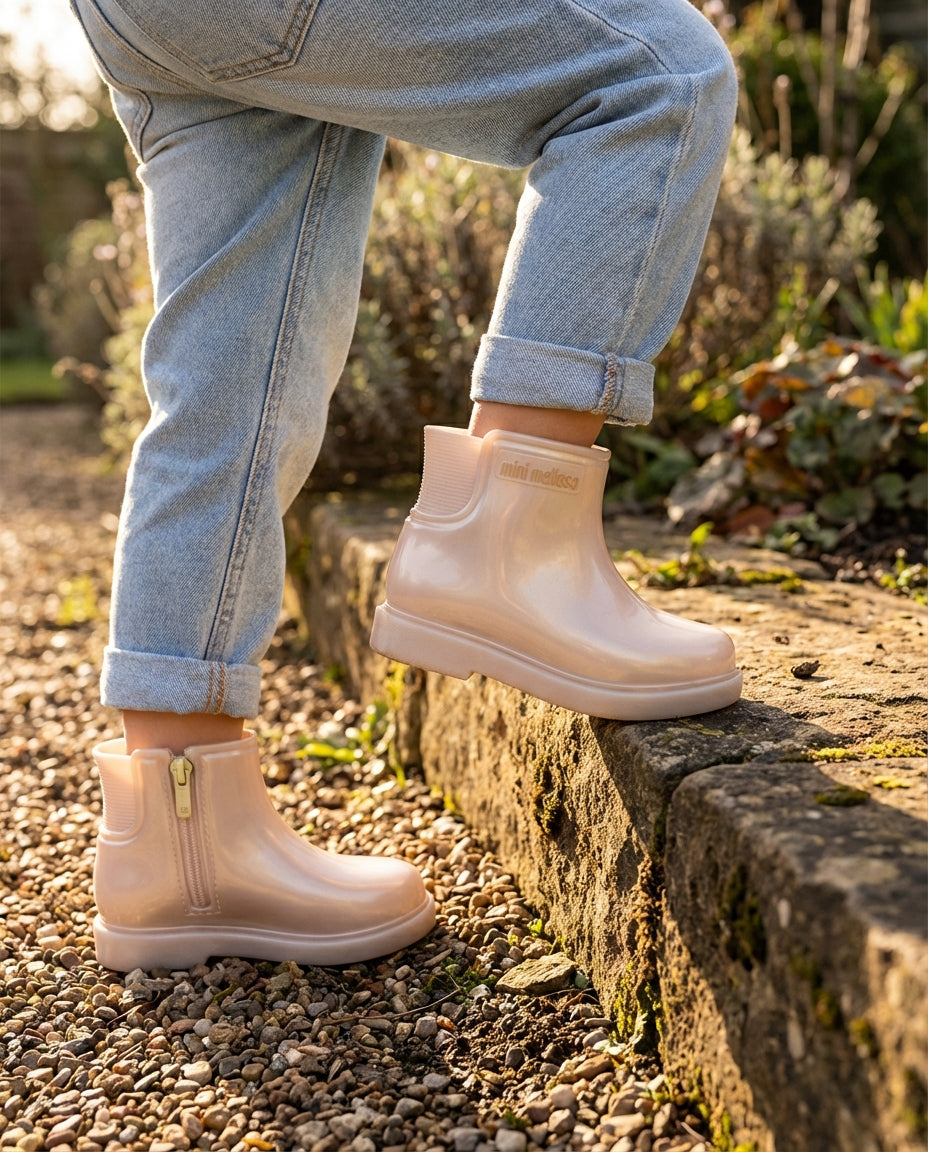 Taş basamağa çıkan çocuğun ayağında esnekliğini ve konforunu sergileyen Mini Melissa bej bebek botu ayak detayı