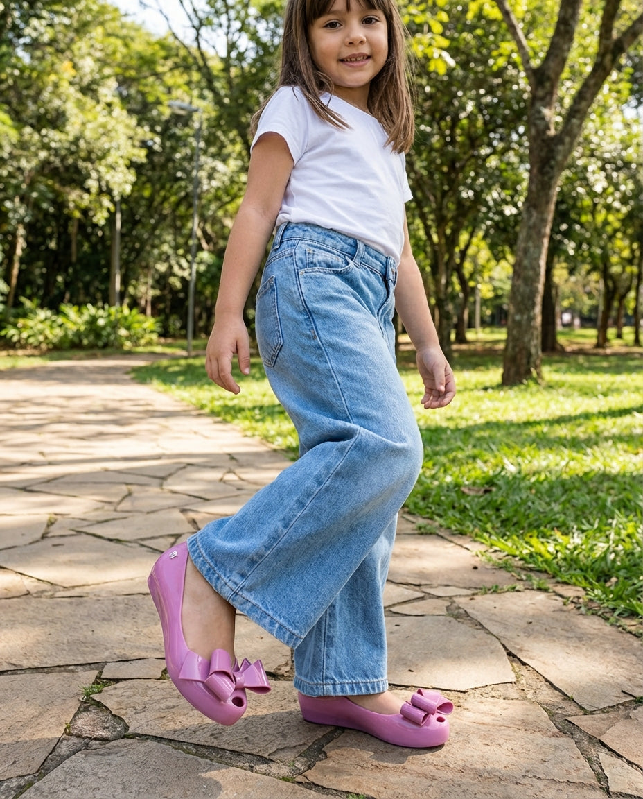 Geniş paça açık mavi kot pantolonla adım atan 6 yaşındaki kızın ayağında zarif Mini Melissa fiyonklu lila babet