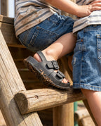 Oyun parkında tırmanırken esneyen ve kaymayan tabanıyla siyah Mini Melissa Cozy çocuk sandaleti