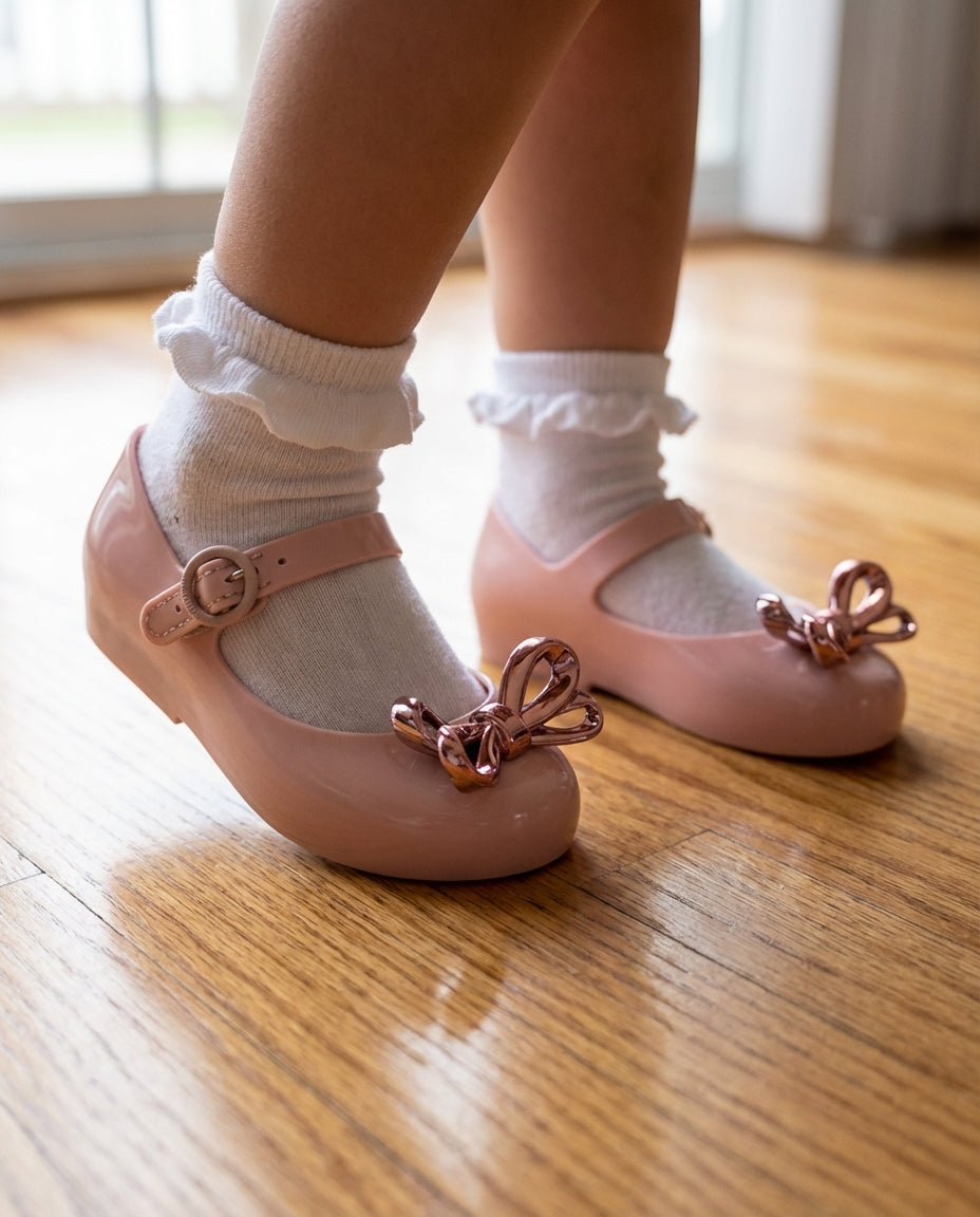 Fırfırlı çorapla adım atan 2 yaşındaki miniğin ayağını güvenle saran pratik cırt cırtlı Mini Melissa pembe metalik ayakkabı yakın plan