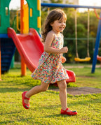 Parkta neşeli adımlarla koşan kız çocuğunun ayağında Mini Melissa Sweet Love picnic kırmızı jel ayakkabı.