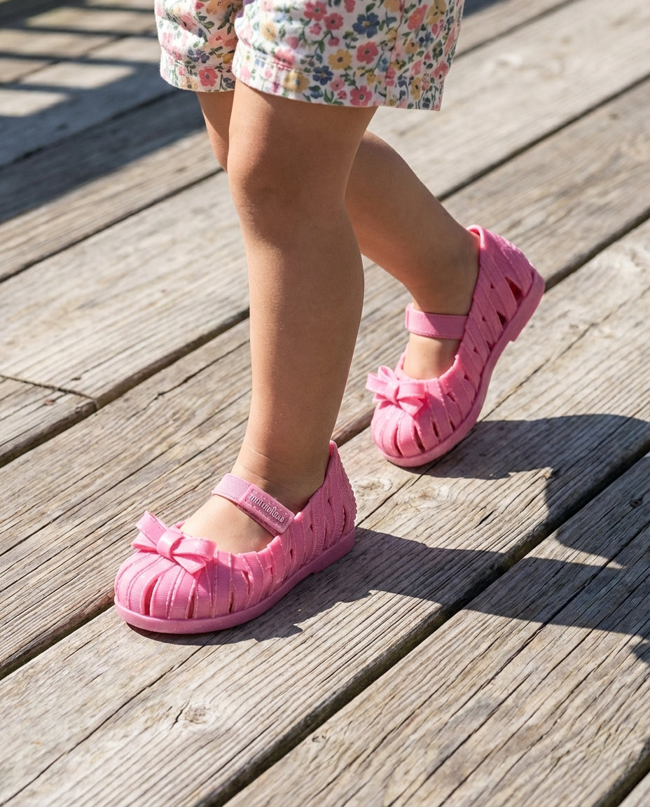 Ahşap zeminde adım atan 2 yaşındaki miniğin ayağını güvenle saran nefes alabilen kafesli Mini Melissa pembe babet yakın plan