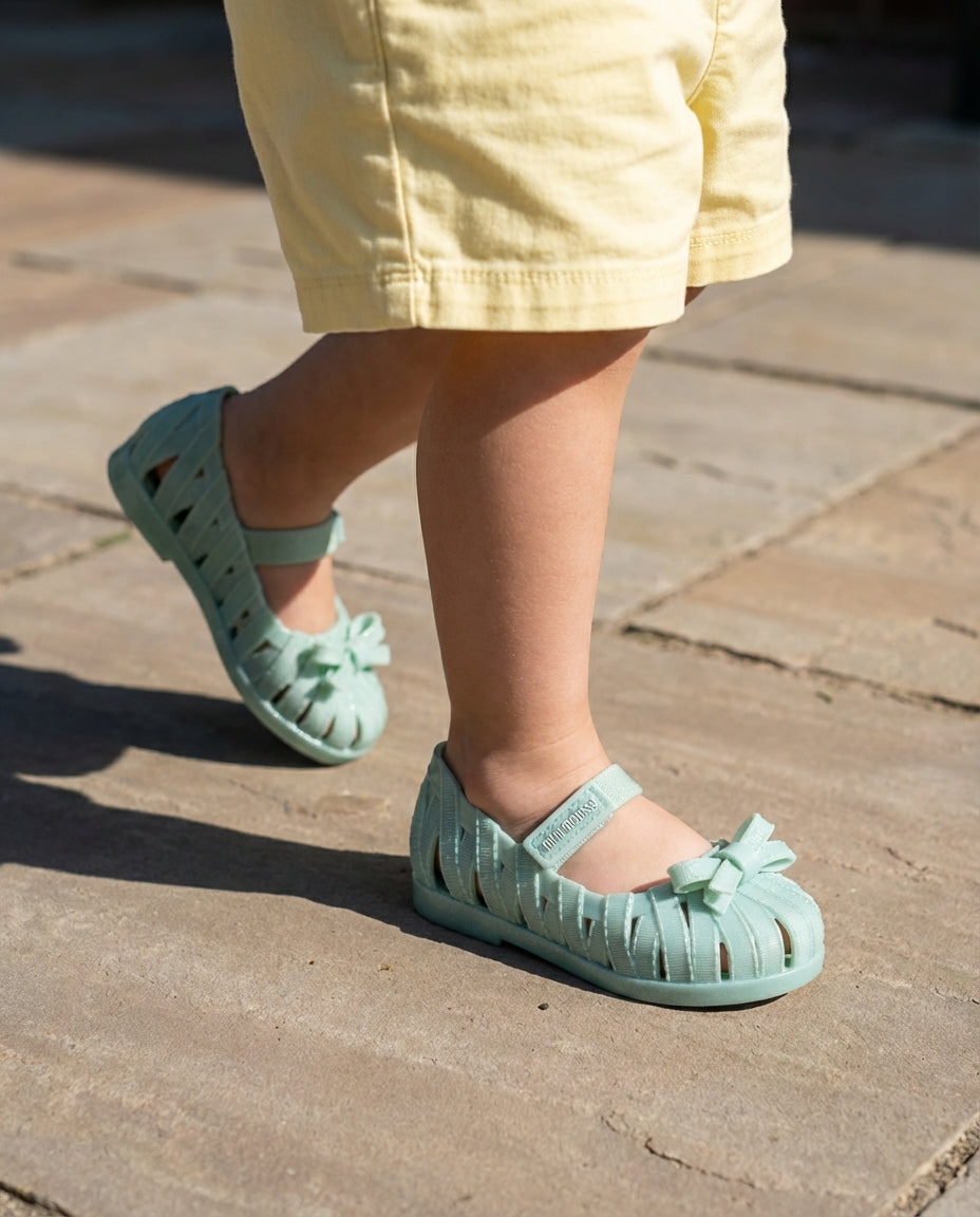 Taş zeminde adım atan 2 yaşındaki miniğin ayağını güvenle saran nefes alabilen kafesli Mini Melissa su yeşili babet yakın plan