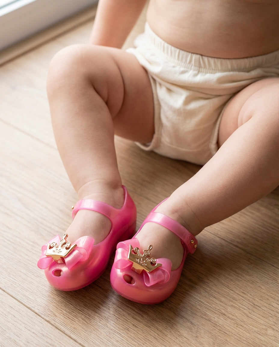 1.5 yaşındaki bebeğin tombiş ayaklarını saran 3D altın taç detaylı sevimli Mini Melissa pembe prenses ilk adım ayakkabısı yakın plan