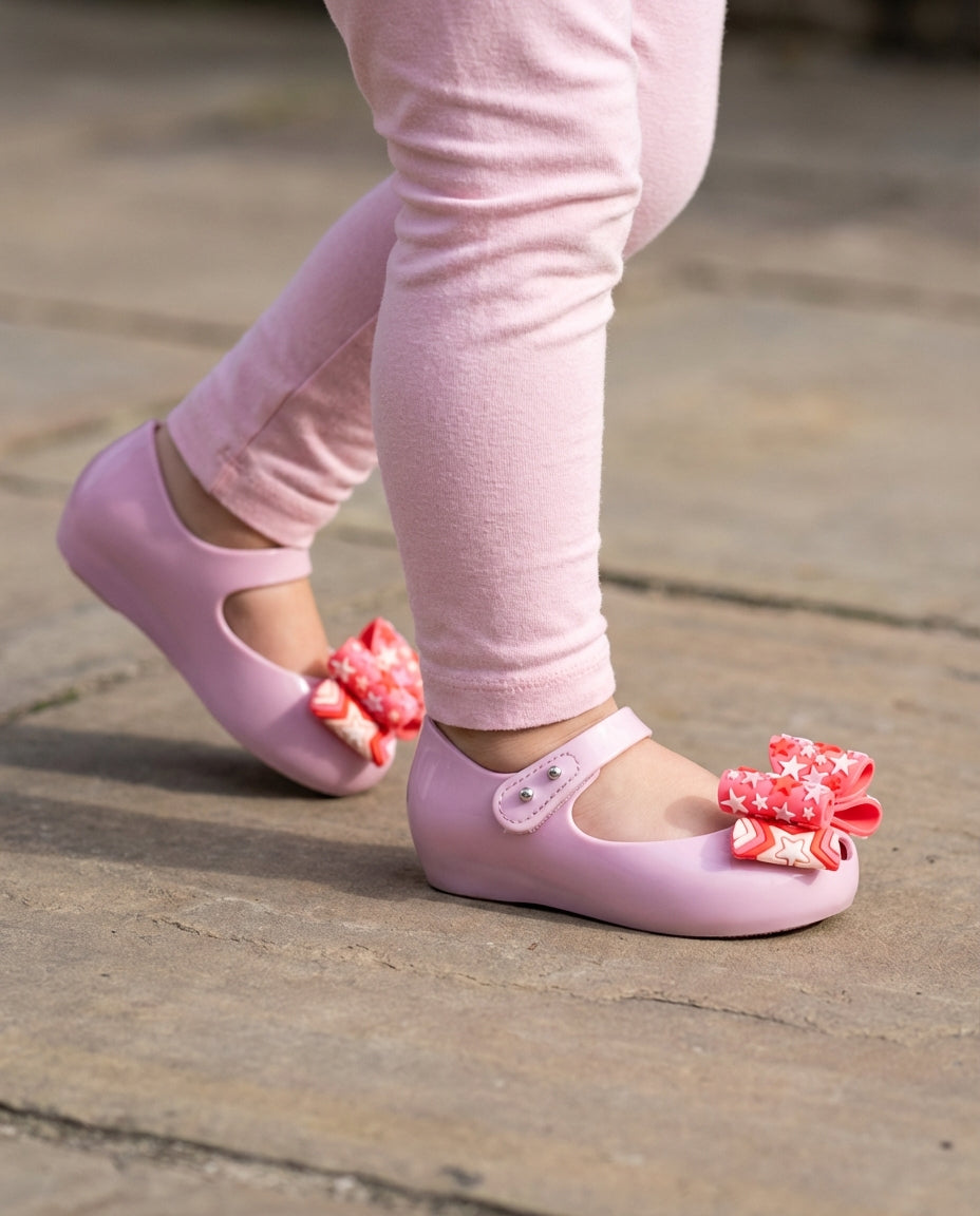 Açık pembe taytla adım atan 2 yaşındaki miniğin ayağını güvenle saran pratik Mini Melissa lila ayakkabı yakın pla