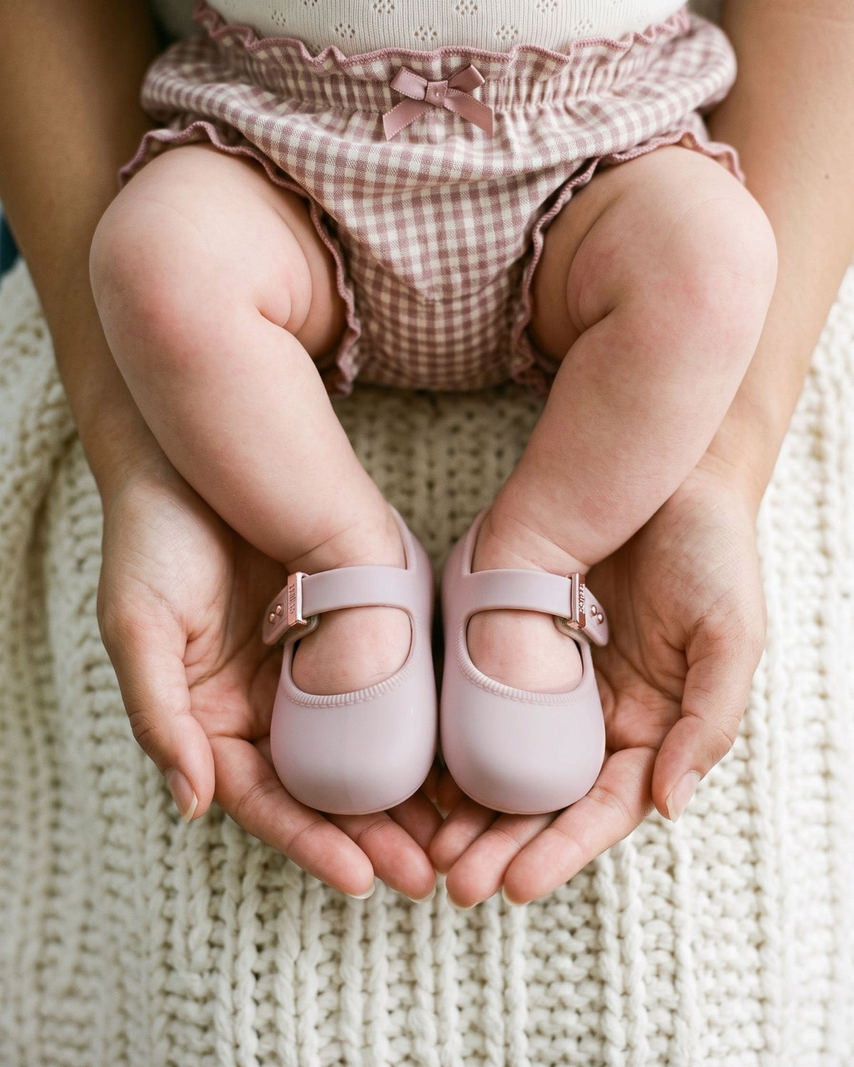 Annesinin avucunda pudra pembe Mini Melissa My First Ballerina giymiş bebek ayakları, 17 numara yenidoğan babeti
