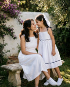 Anne ve kızı bahçede, kız Monna Rosa beyaz uzun poplin elbise ve fiyonk toka ile