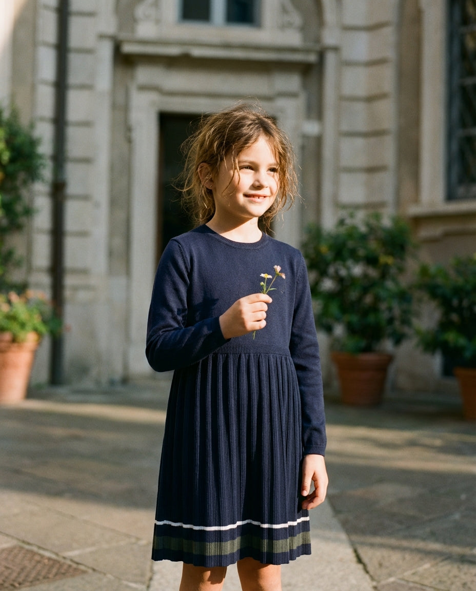 Avrupa sokağında duran 8 yaşındaki kız çocuğunun üzerindeki lacivert Monna Rosa Milano organik pamuk triko elbise yakın plan, doğal film karesi