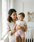 Aydınlık bebek odasında Türk anne kucağında Little Princess yazılı organik pamuk pointel set giymiş bebeği