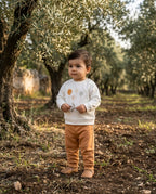 Zeytinlikte ayakta duran Türk bebeği, organik pamuk balon desenli uzun kollu sweatshirt ve tarçın pantolon giymiş