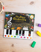 Ahşap masa üzerinde The Story Orchestra I Can Play kitabı, yanında renkli oyuncak bloklar